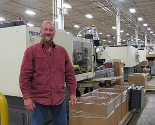Rodon employee stands in front of a Nissei machine in our facility