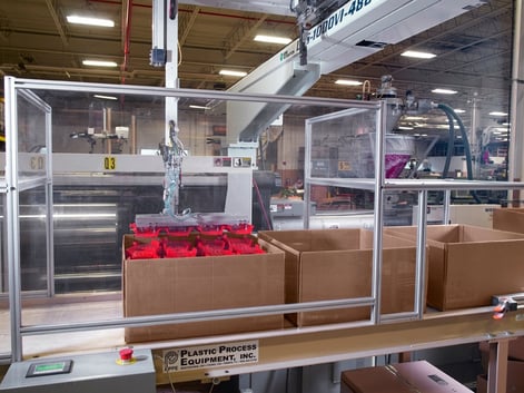 plastic injection molded parts being stacked in a box by an automated arm