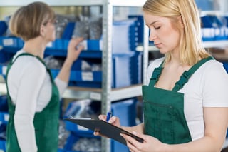 Young blond woman is checking the product list in the inventory room